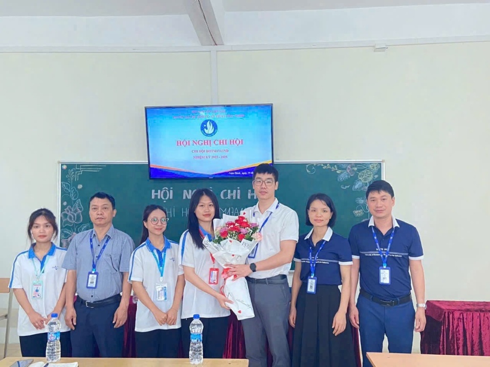 A group of people standing in front of a blackboard Description automatically generated