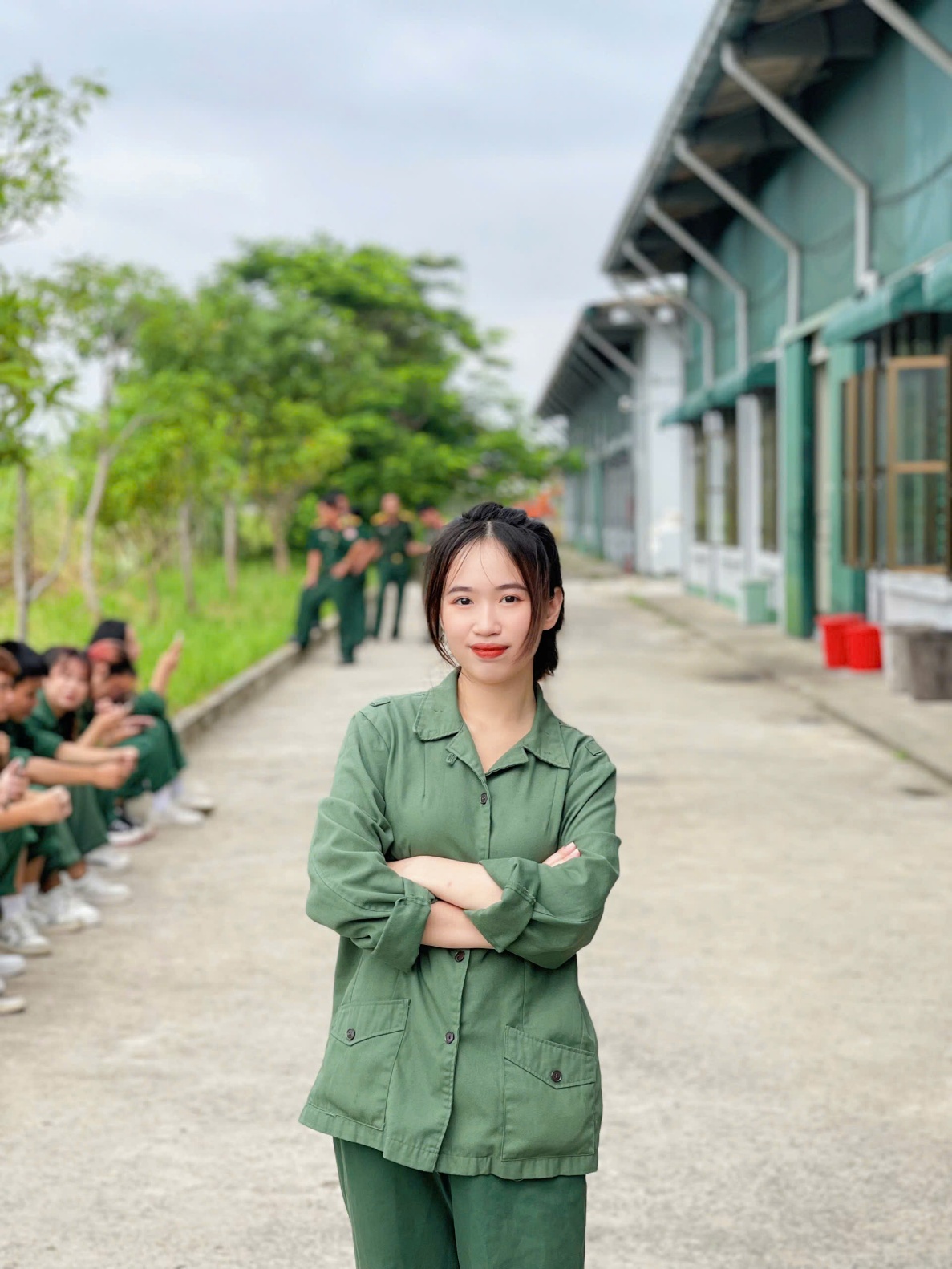 A person in green uniform standing on a sidewalk with a group of people in the background AI-generated content may be incorrect.