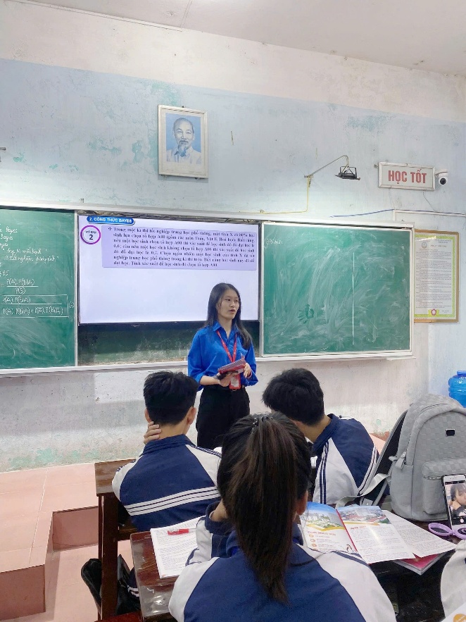 A person standing in front of a classroom Description automatically generated
