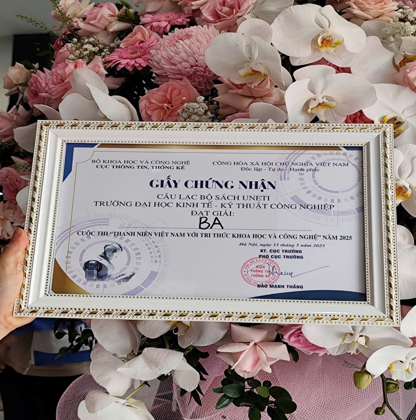 A hand holding a frame with flowers AI-generated content may be incorrect.