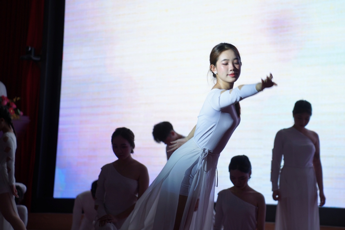 A person in white dress dancing with other people in the background AI-generated content may be incorrect.