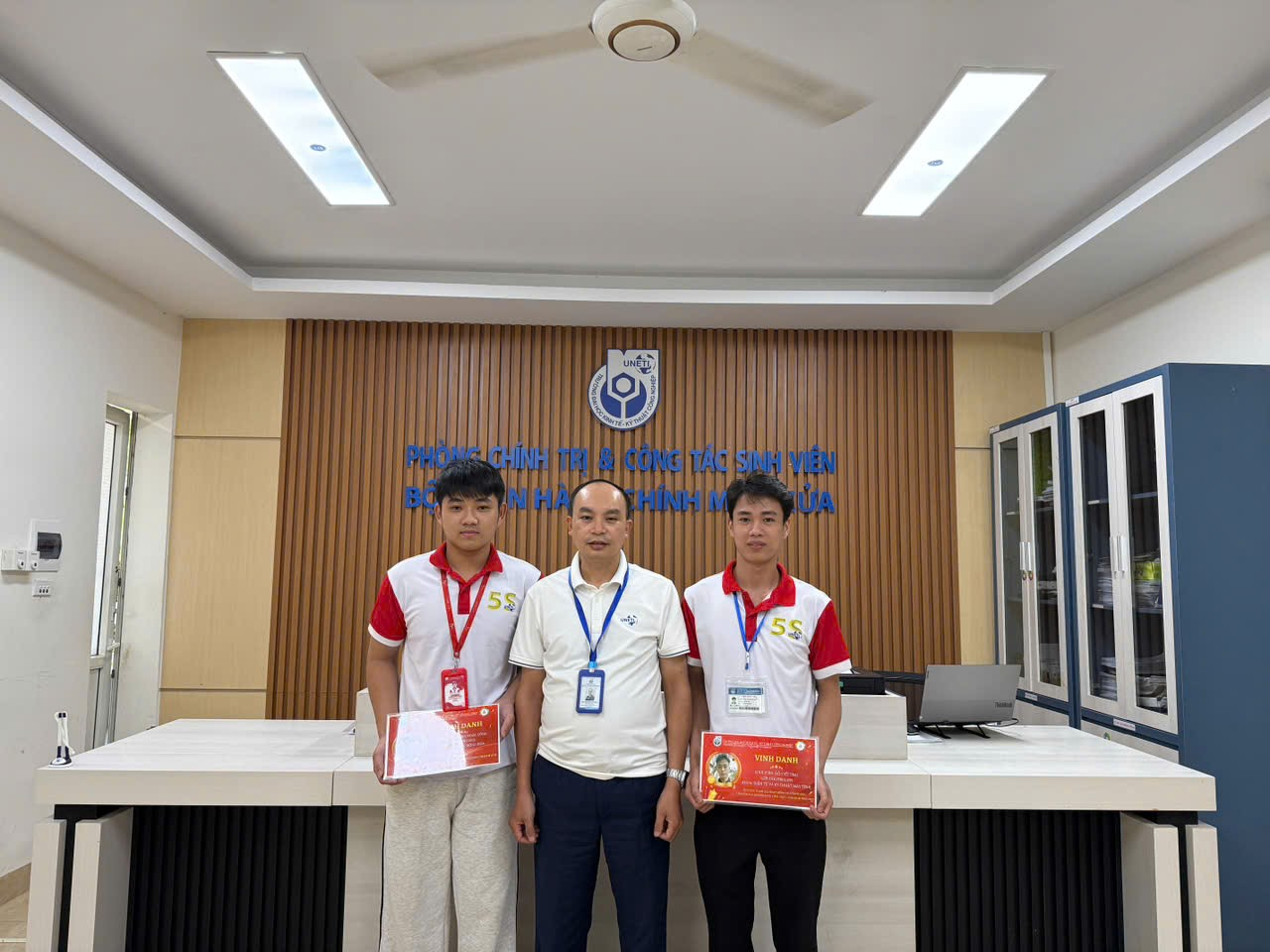 A group of men standing in front of a desk

Description automatically generated