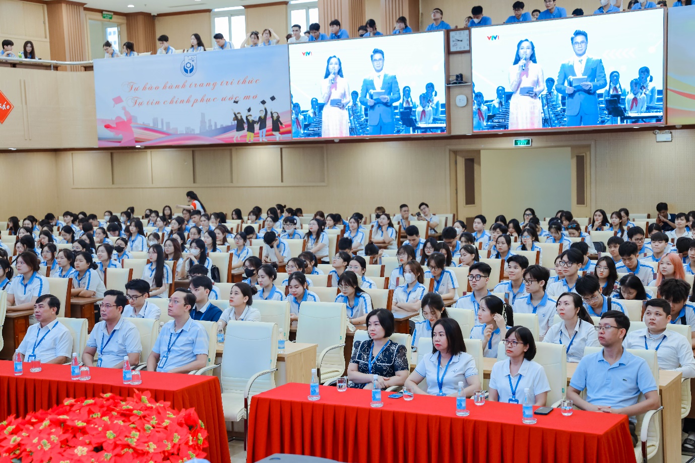 A group of people sitting in chairs in a room with a large screen Description automatically generated