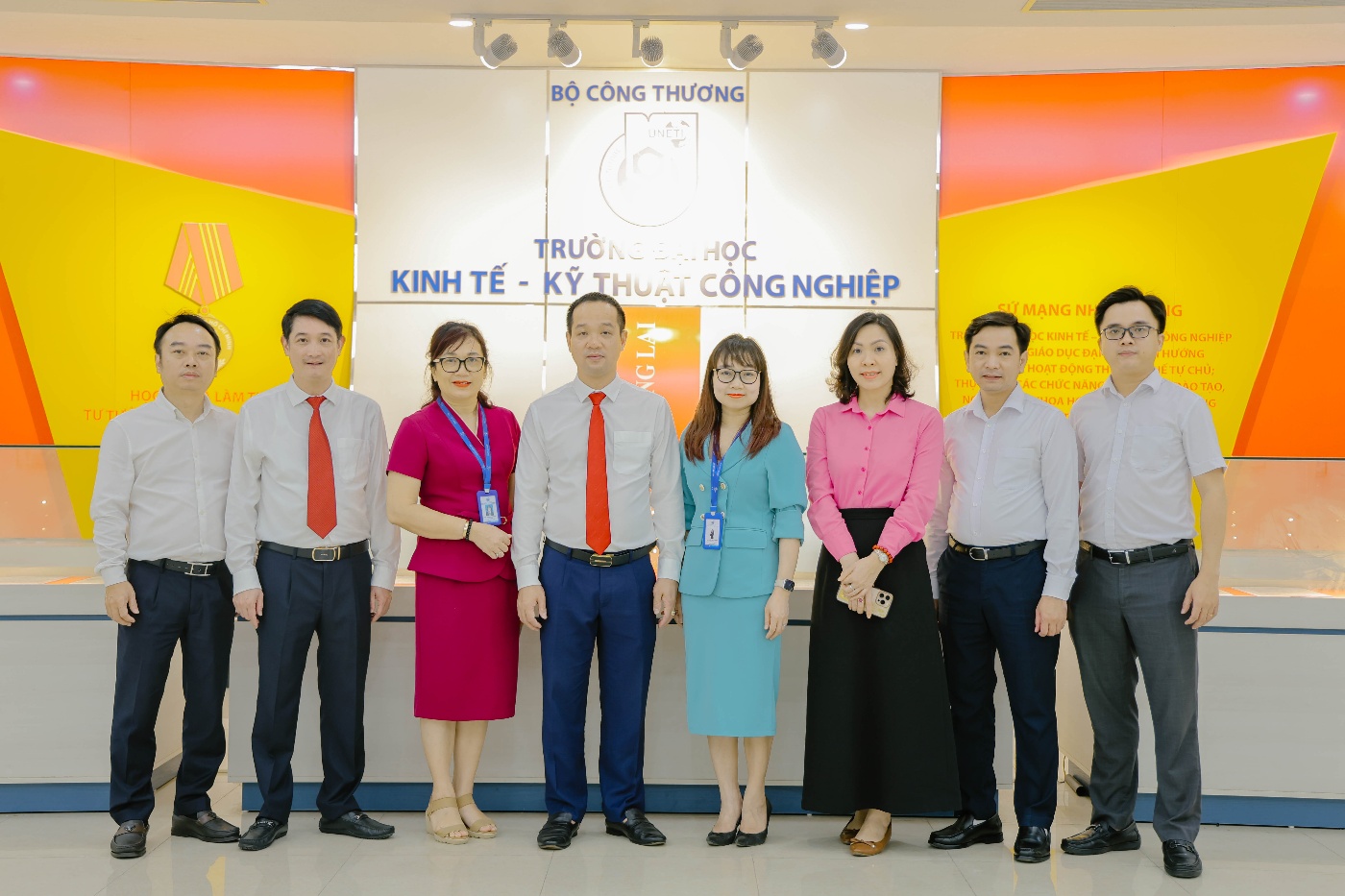 A group of people standing in front of a sign Description automatically generated