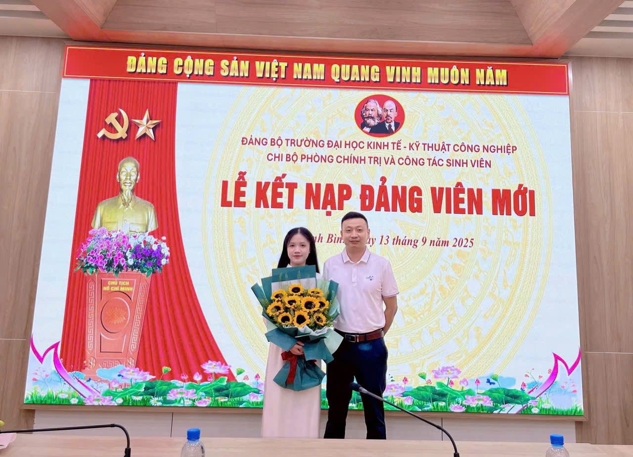 A person and person standing in front of a large screen Description automatically generated