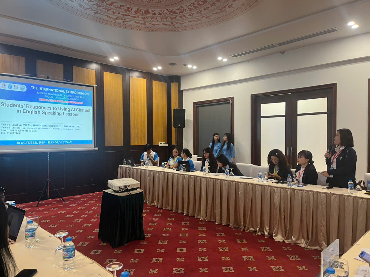 A group of people sitting at a table in a room with a projector screen AI-generated content may be incorrect.