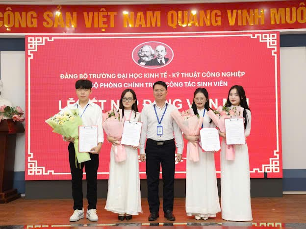 A group of people standing in front of a red banner

Description automatically generated