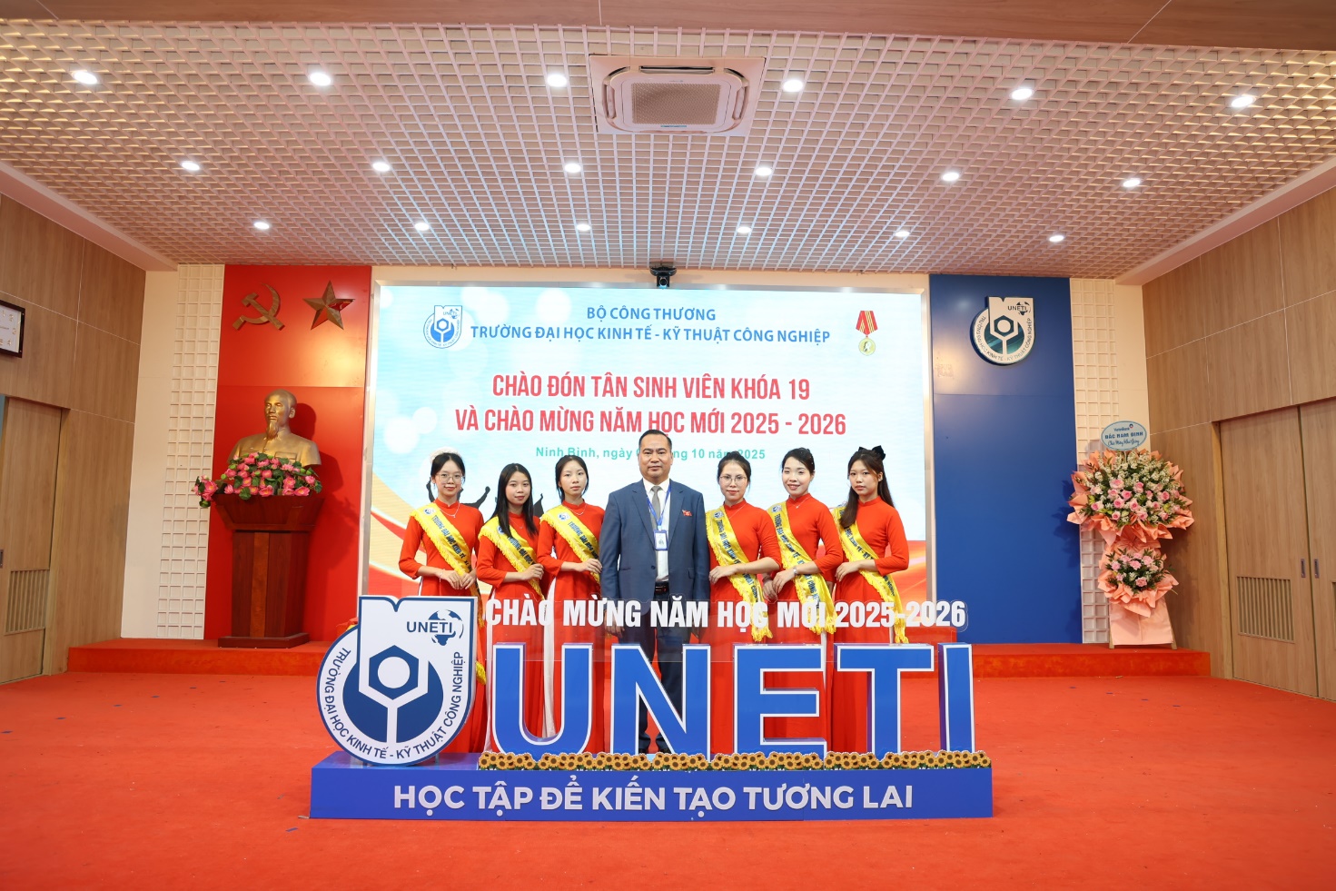A group of people standing in front of a sign Description automatically generated