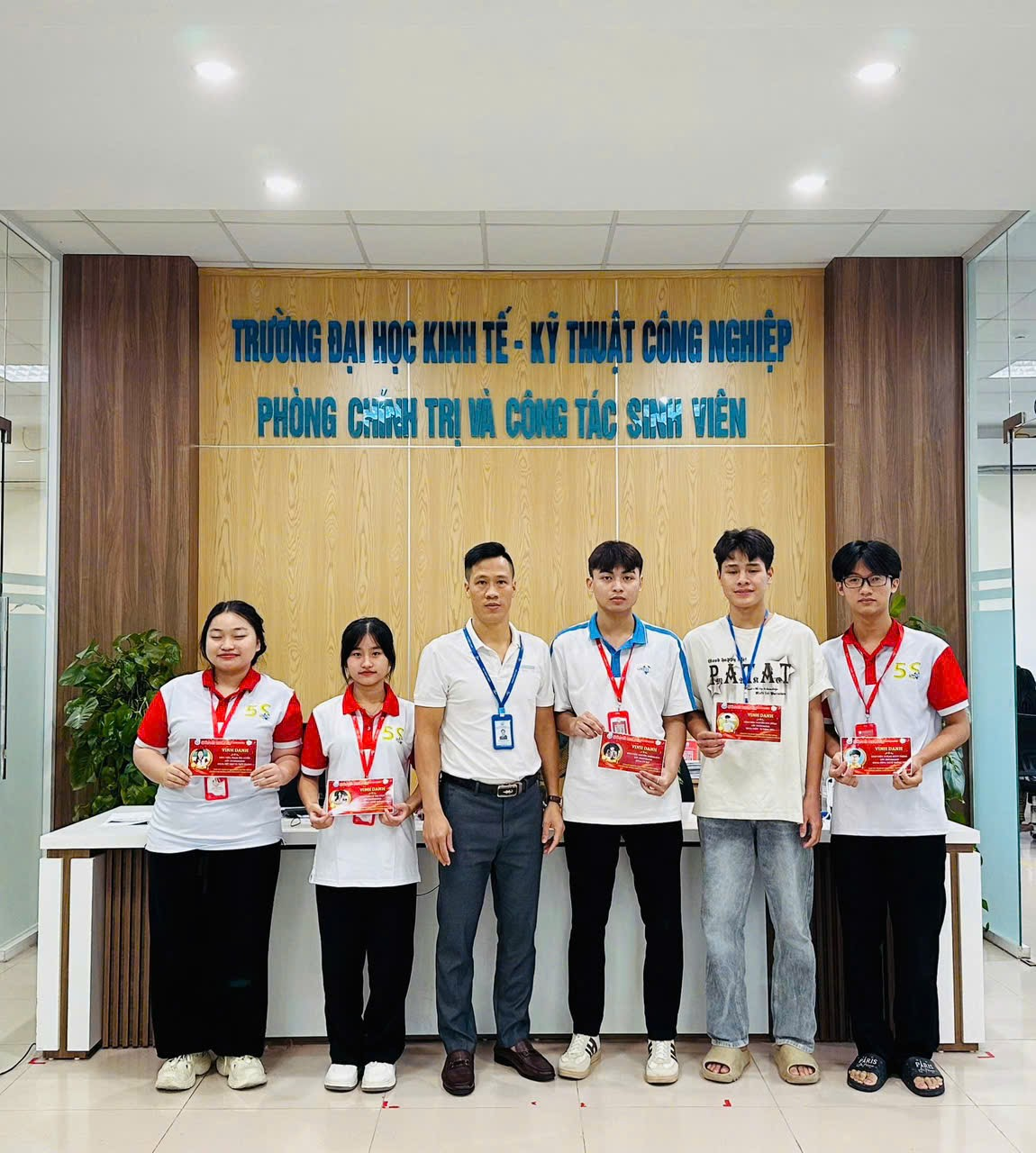 A group of people standing in front of a wall Description automatically generated