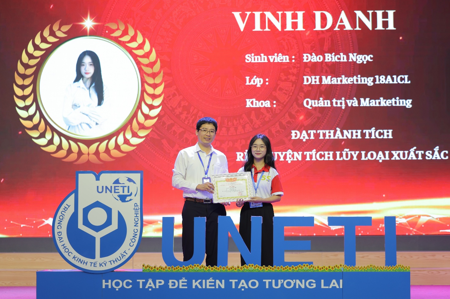 A person and person standing on a stage Description automatically generated