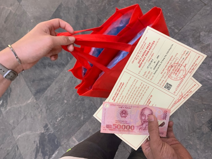 A person handing over a red shopping bag to a person holding a red shopping bag AI-generated content may be incorrect.