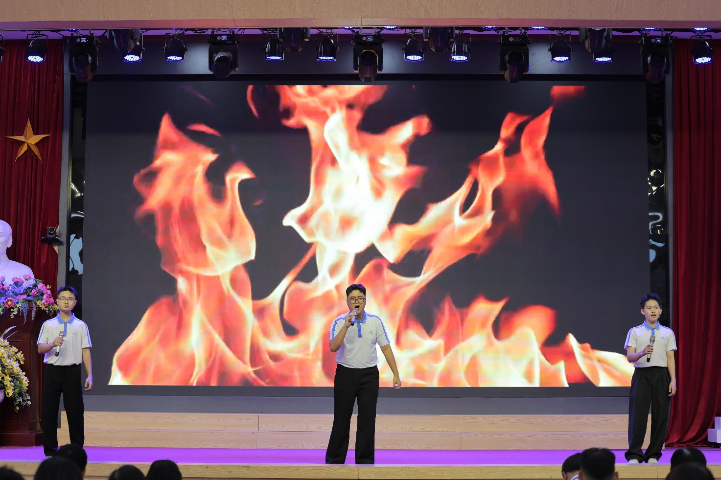 A person on stage with microphone Description automatically generated