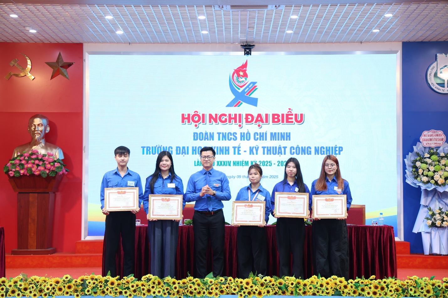 A group of people standing on a stage holding certificates Description automatically generated