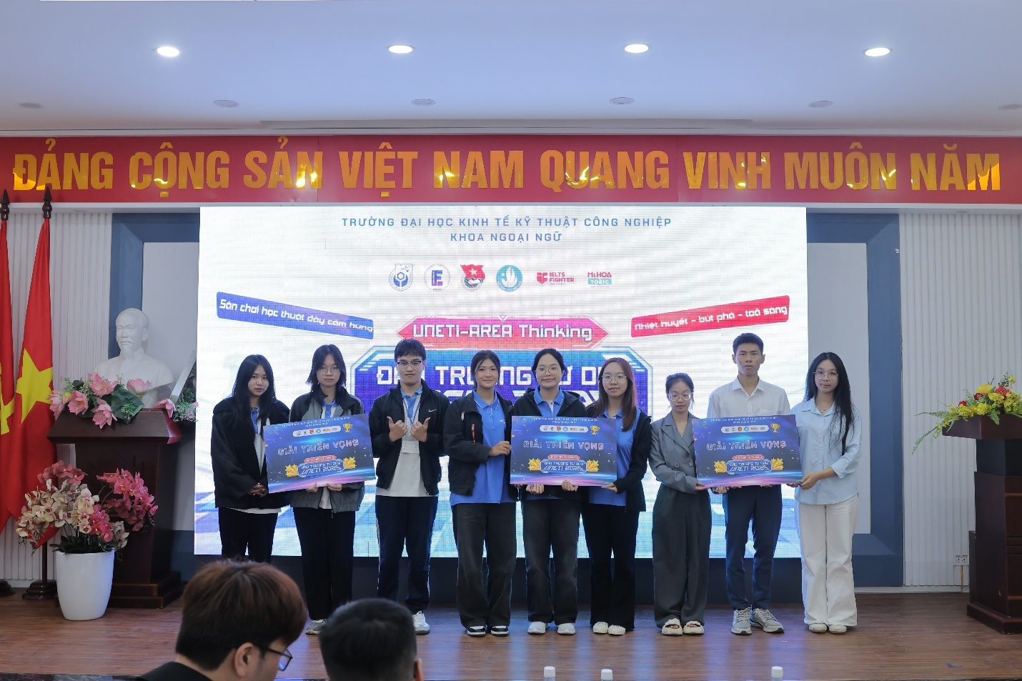 A group of people standing on a stage holding signs AI-generated content may be incorrect.