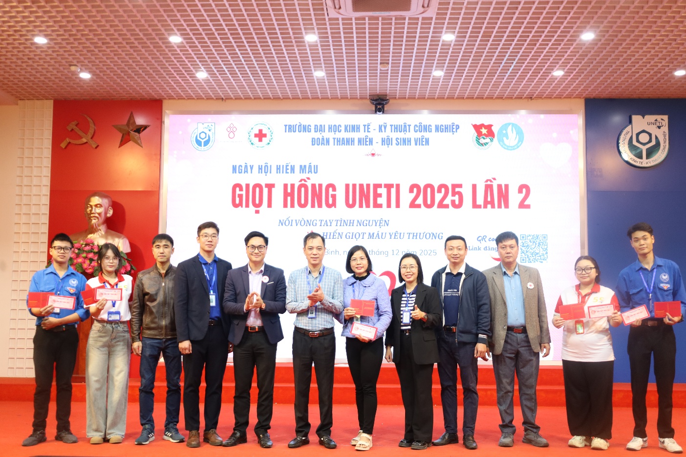 A group of people standing in front of a banner

Description automatically generated