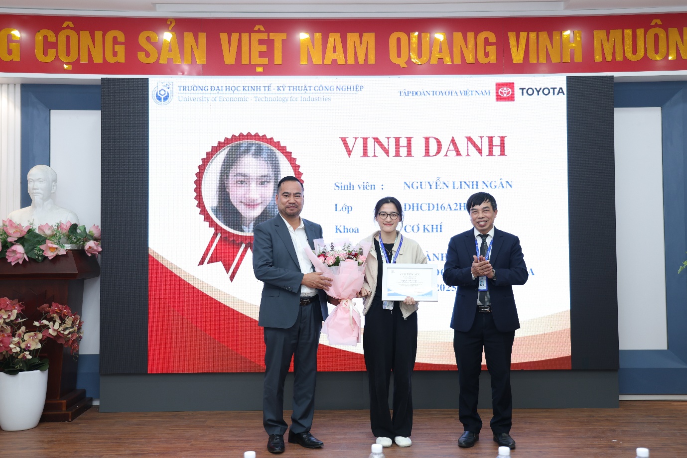 A group of people standing in front of a large screen Description automatically generated