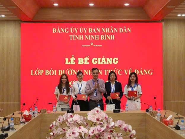 A group of people standing in front of a red backdrop Description automatically generated