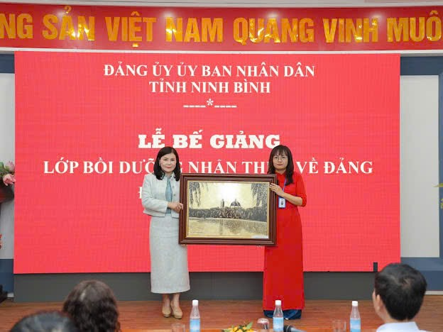 A group of women holding a framed painting Description automatically generated