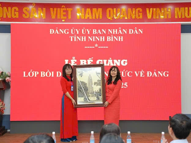 A group of women holding a framed picture Description automatically generated