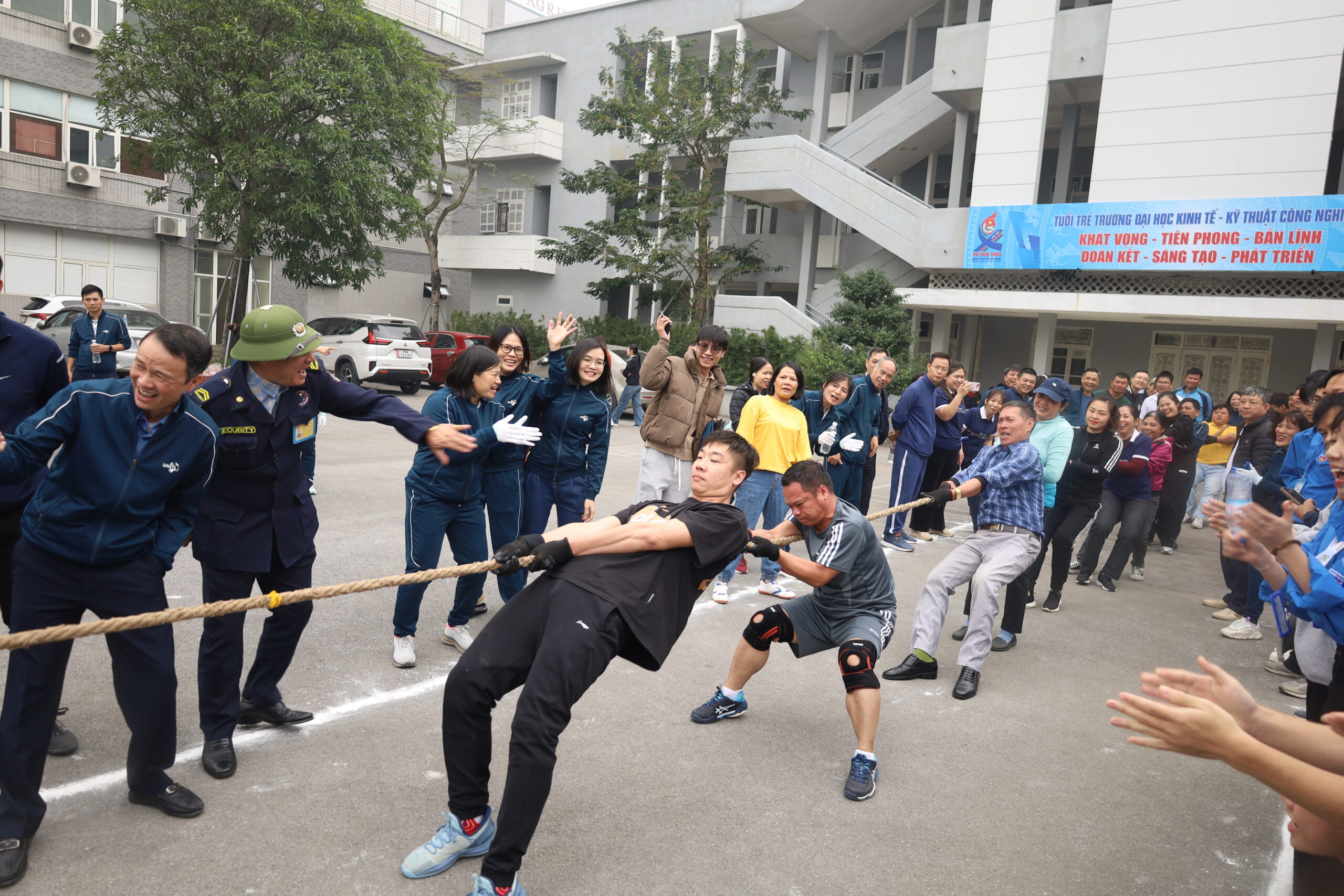 A person pulling a rope with a group of people in the background

Description automatically generated