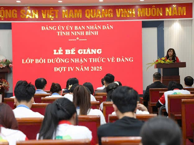 A person speaking to a group of people in a lecture hall Description automatically generated