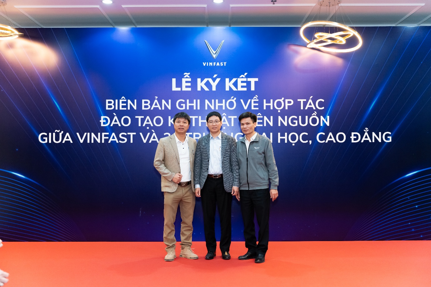 A group of men standing in front of a blue sign

Description automatically generated