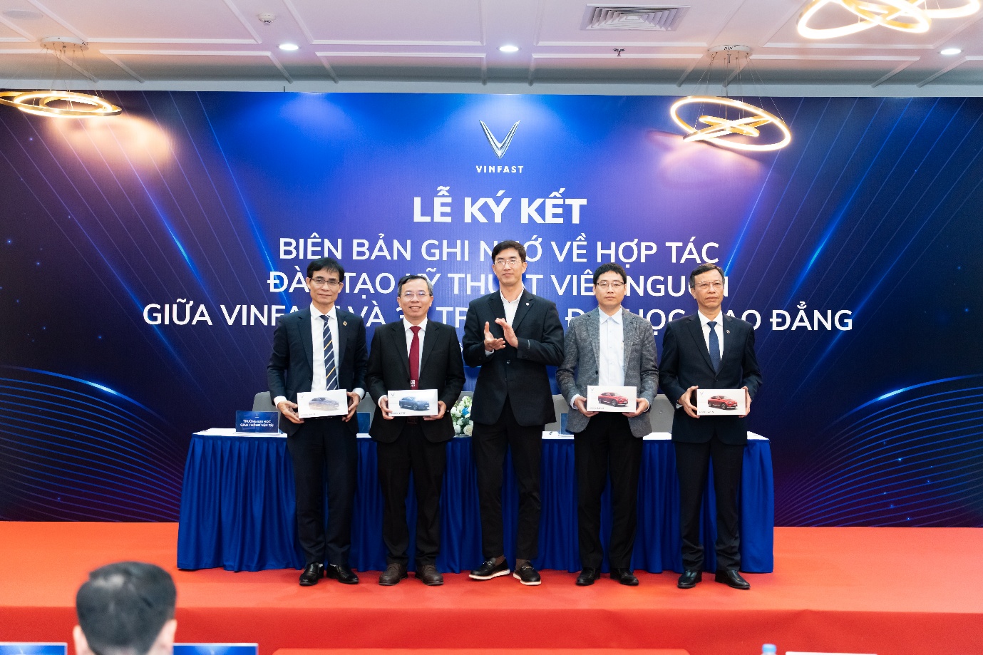 A group of men standing on a table with awards

Description automatically generated