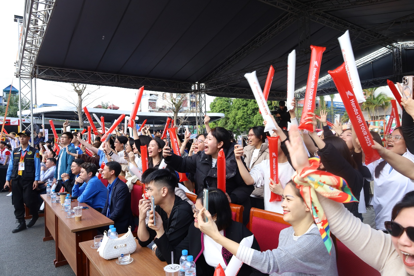A group of people holding up red and white objects Description automatically generated