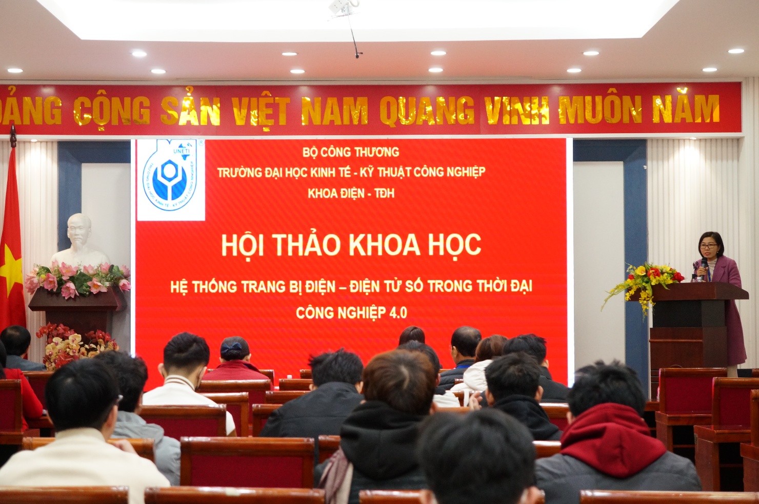 A group of people sitting in chairs in front of a red banner

Description automatically generated