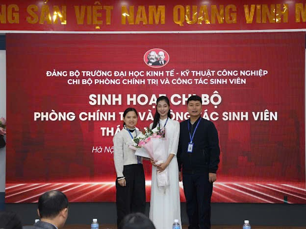 A group of people standing in front of a red banner
Description automatically generated