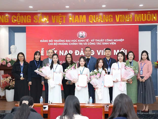 A group of people standing in front of a red banner
Description automatically generated