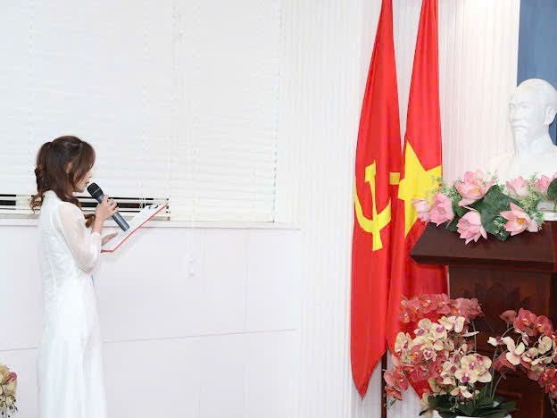A person in a white dress speaking into a microphone
Description automatically generated