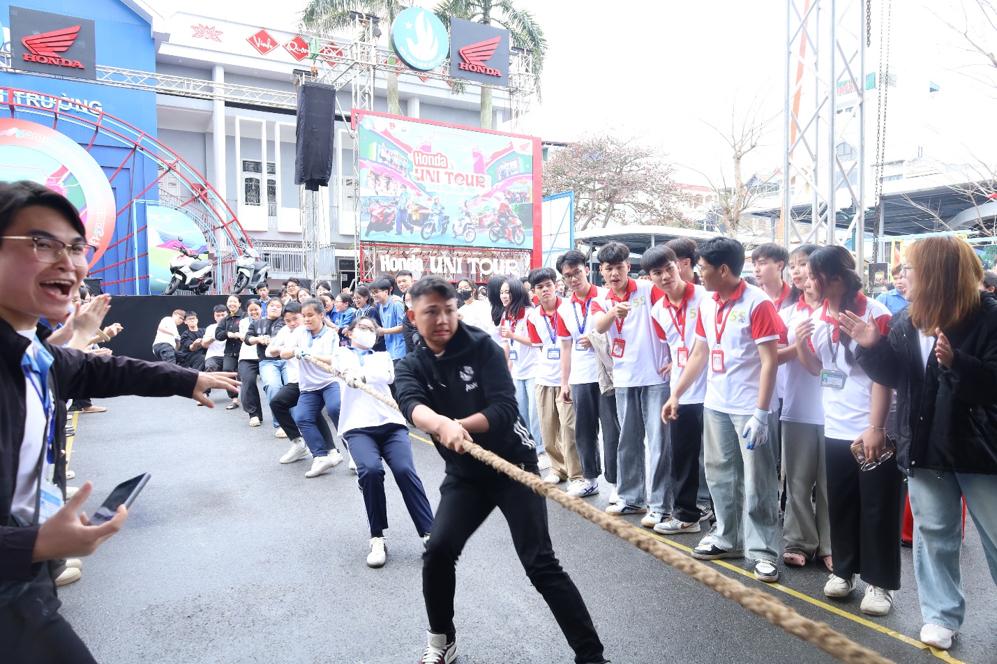A person pulling a rope with a group of people in the background Description automatically generated