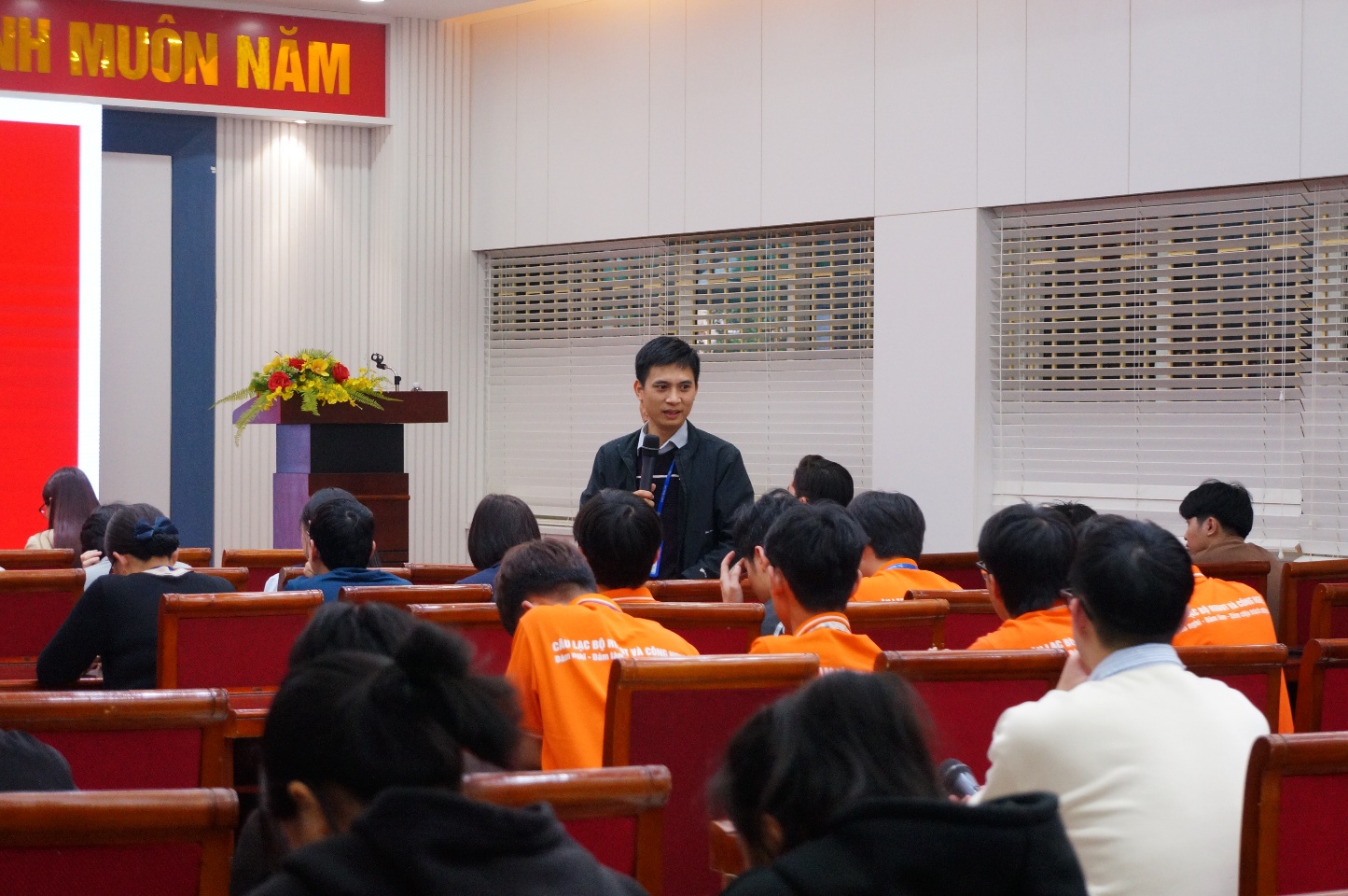 A person speaking to a group of people Description automatically generated