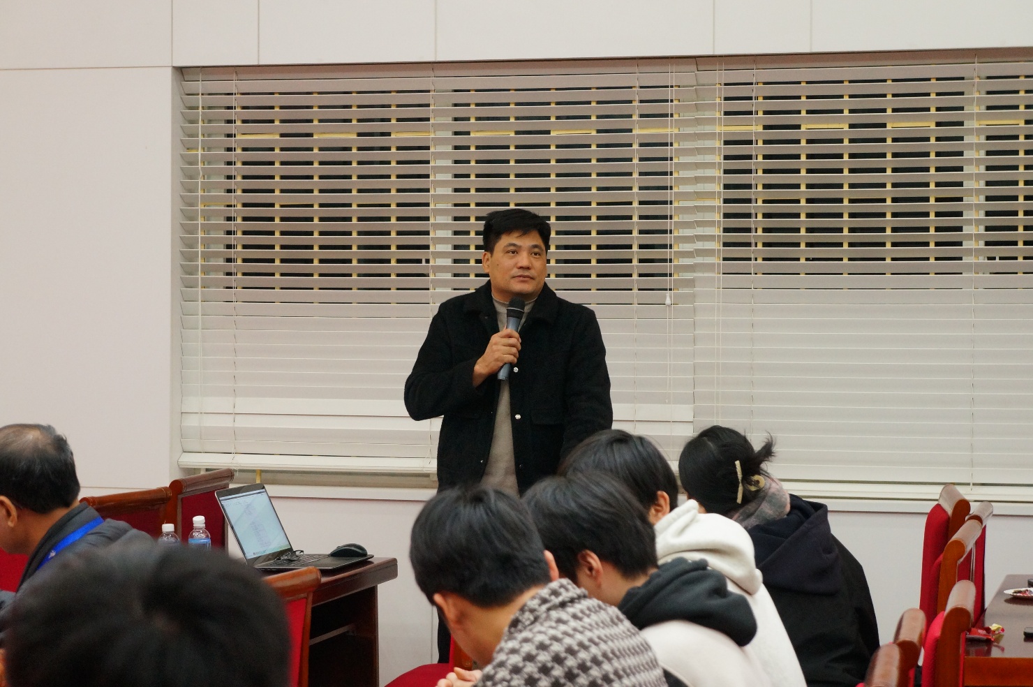A person standing in front of a group of people

Description automatically generated