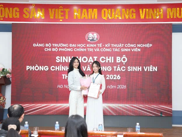Two women standing in front of a red banner
Description automatically generated