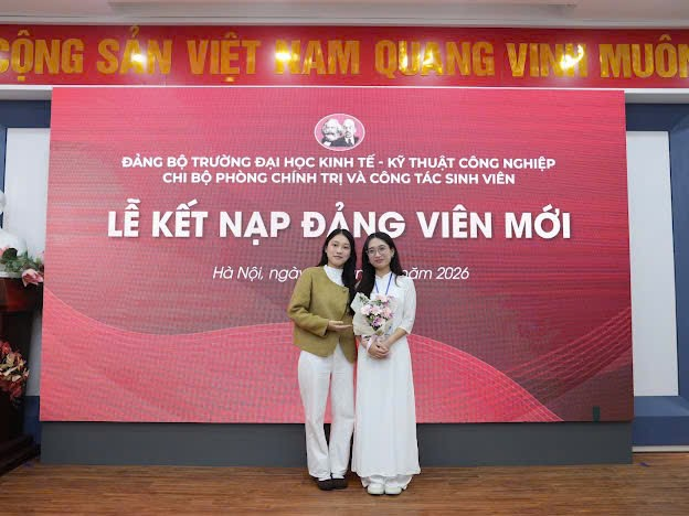 Two women standing in front of a large sign Description automatically generated