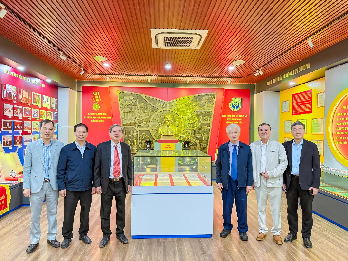 A group of men standing in a room with a display case Description automatically generated