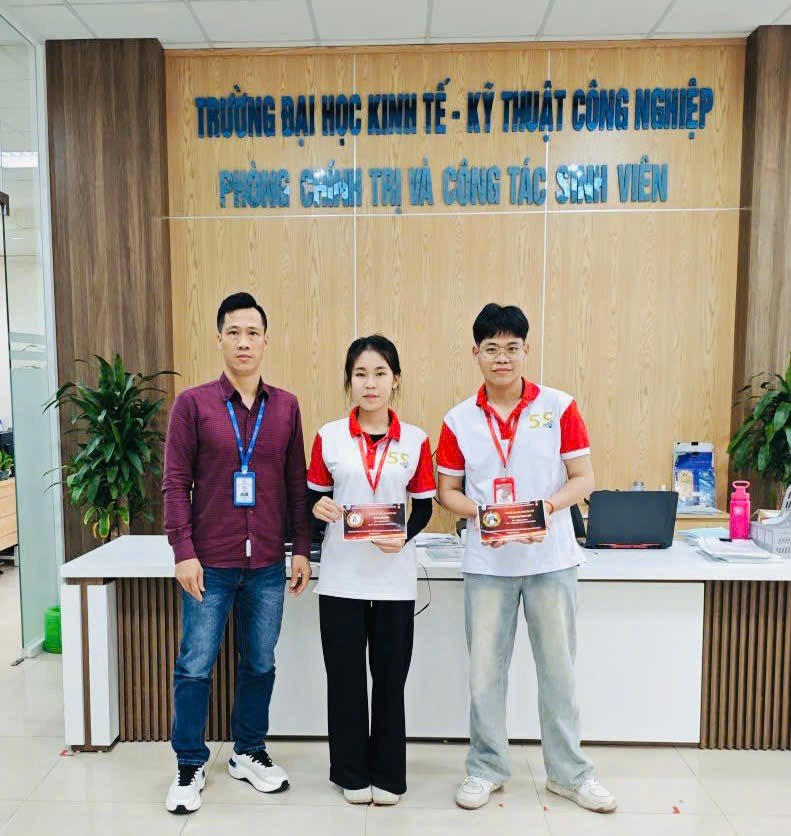 A group of people standing in front of a desk
Description automatically generated