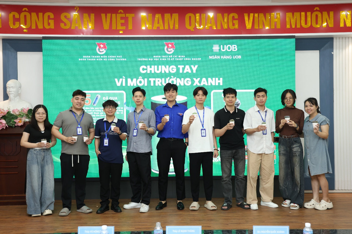 A group of people standing in front of a large screen Description automatically generated