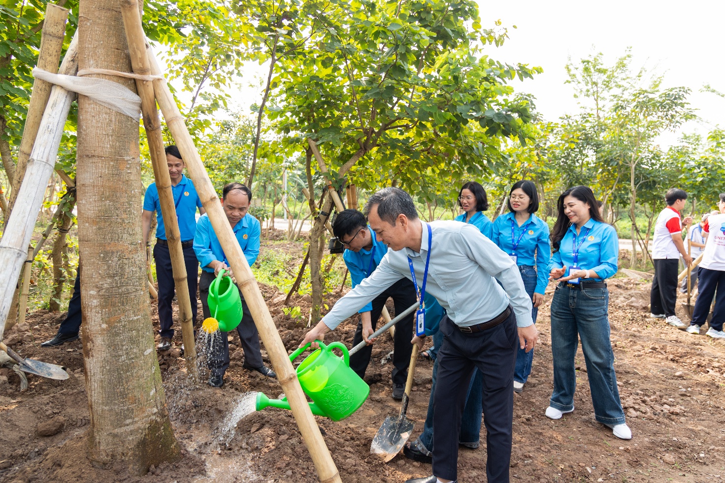 A group of people watering trees Description automatically generated