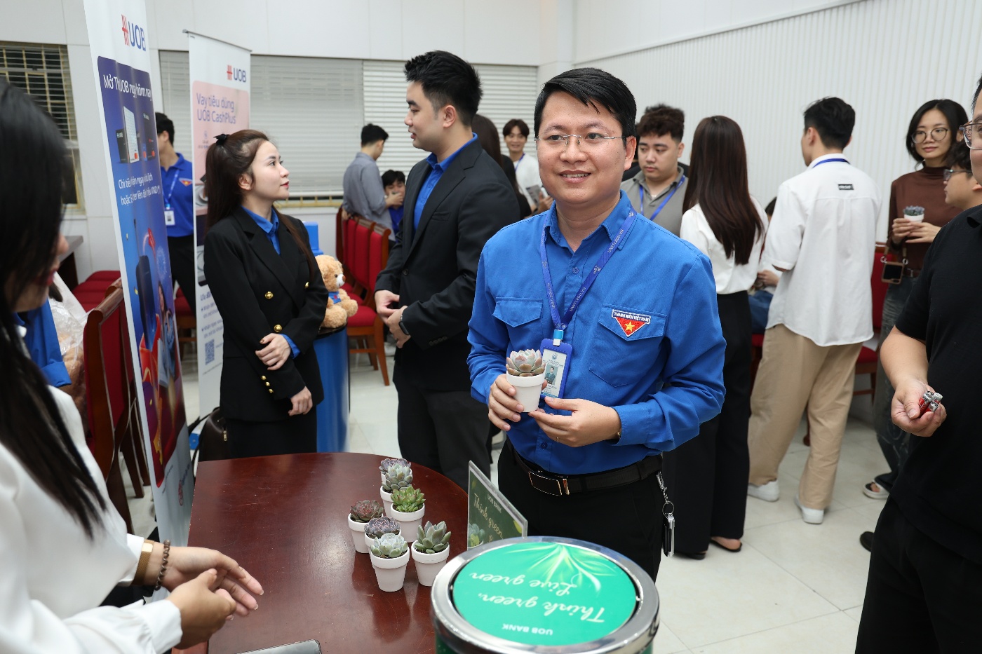 A person in a blue shirt holding a cup of coffee Description automatically generated