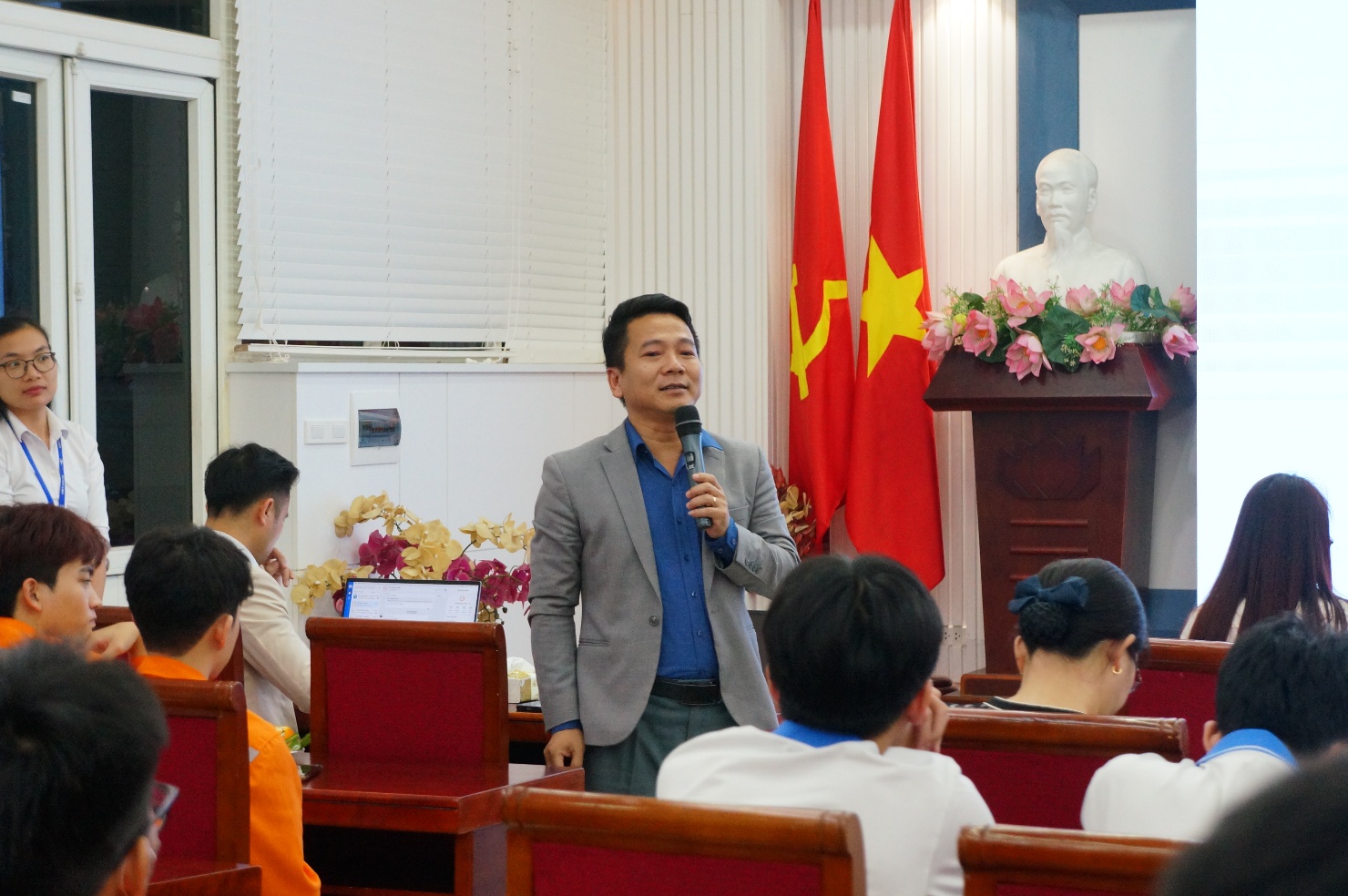 A person standing in a room with a microphone
Description automatically generated