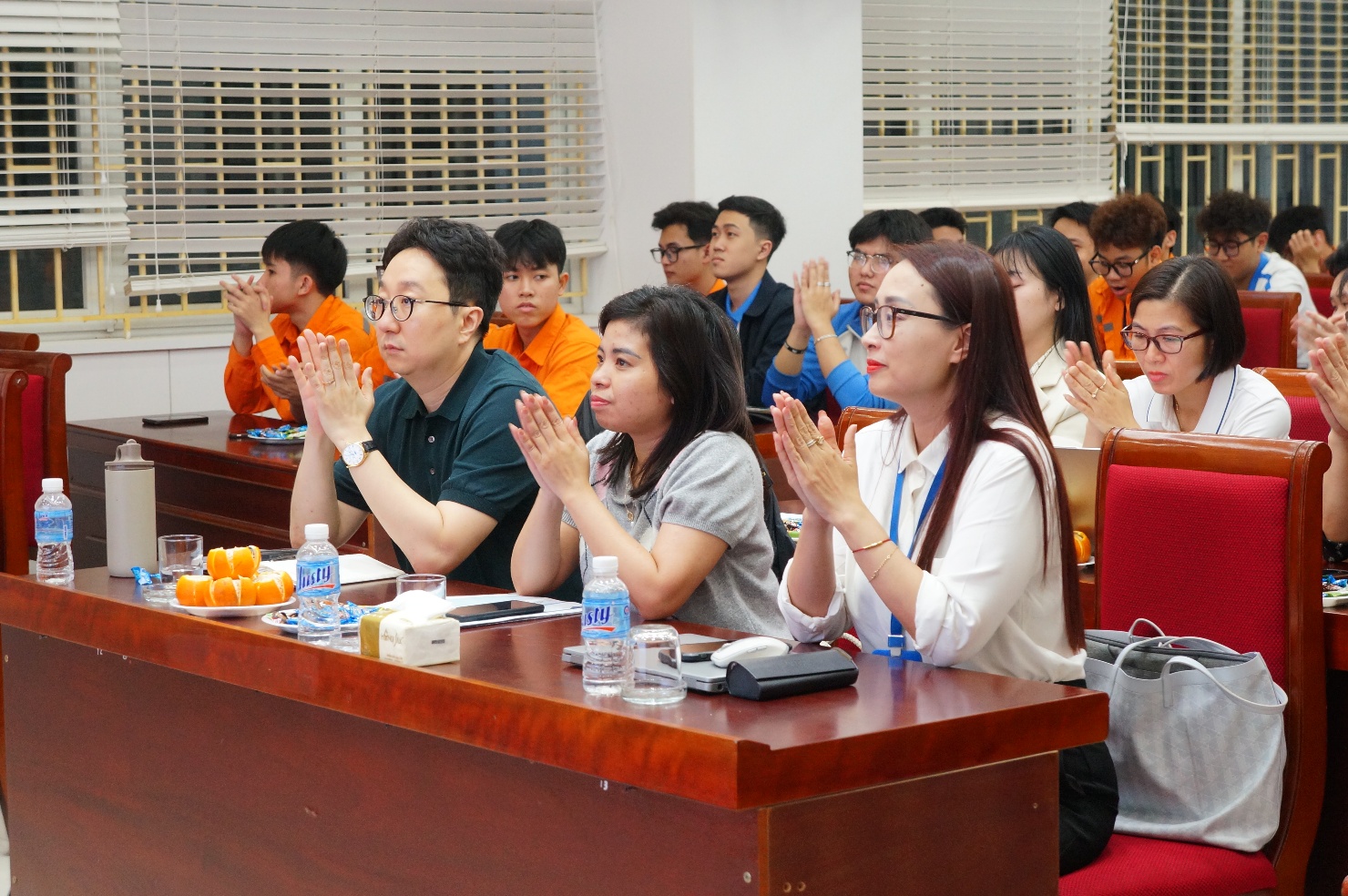 A group of people clapping at a table Description automatically generated