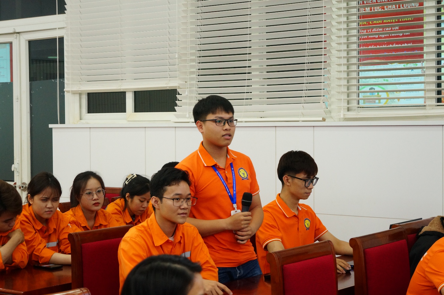 A group of people in orange shirts Description automatically generated