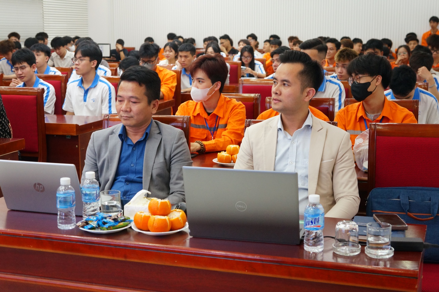 A group of people sitting in a room with laptops and fruit Description automatically generated