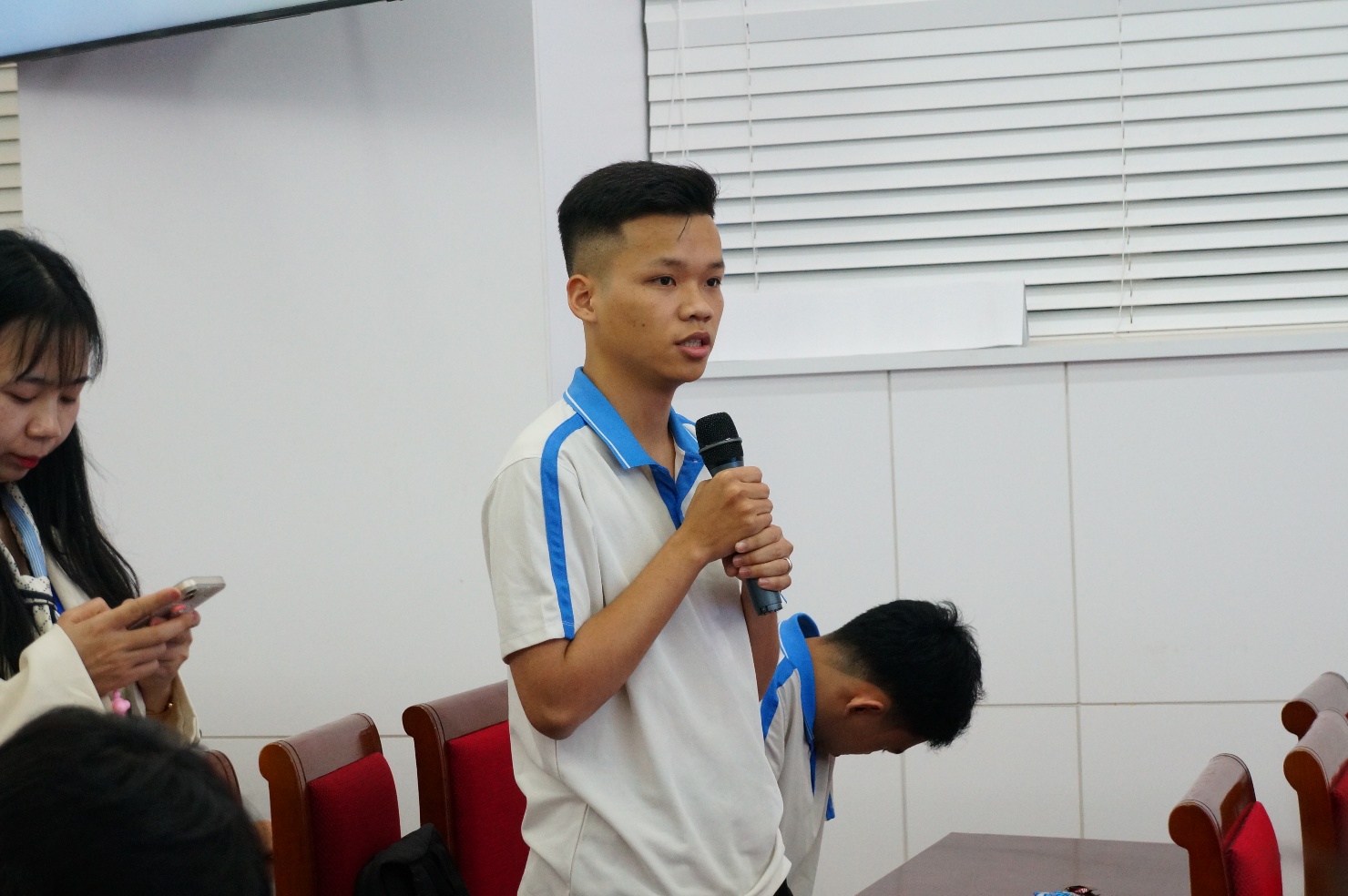 A person holding a microphone Description automatically generated