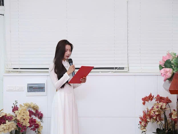 A person in a white dress holding a microphone
Description automatically generated