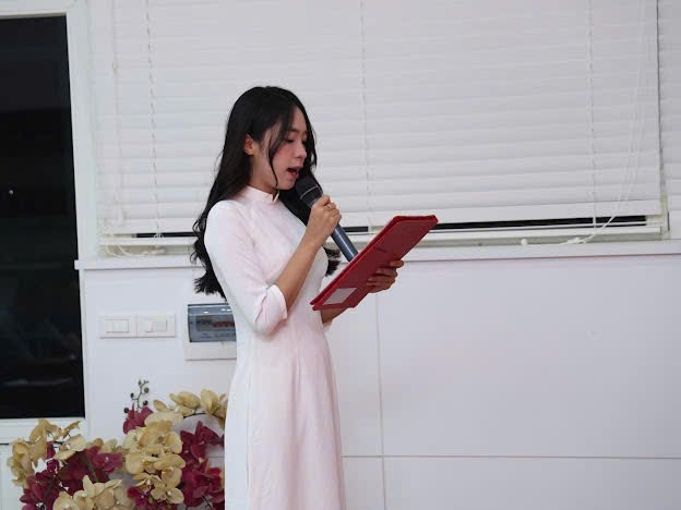 A person in a white dress holding a microphone
Description automatically generated