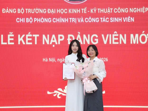 Two women standing in front of a large sign
Description automatically generated